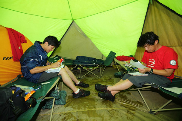 Katsumi Hamura and Hiroyuki Sugiura study their road books in the tent.