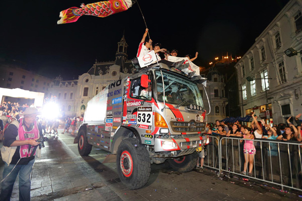 Hino team mechanics ride on the truck's roof to celebrate the goal ceremony.