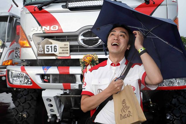 Umbrella in hand, Teruhito Sugawara waits for his truck's turn at the inspections.