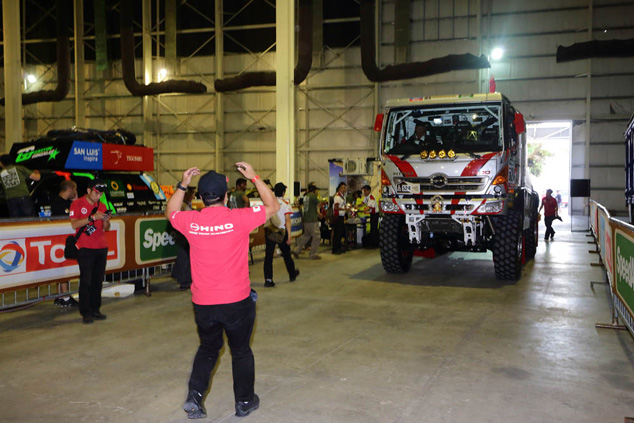 A mechanic guides Car 1 into the vehicle inspection area.