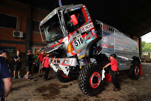 A mechanic tilts the truck's cab for organizers to apply regulation seals.