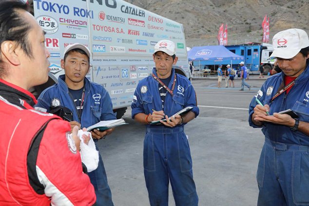 Mechanics listen to Teruhito Sugawara as he describes how his truck is doing.